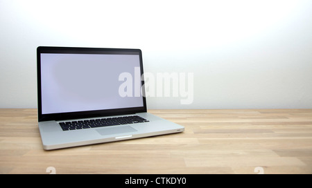 An opened black-and-white lap top with blank screen placed against a white wall Stock Photo