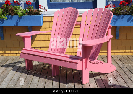 Wooden adirondack chairs on a deck overlooking the water