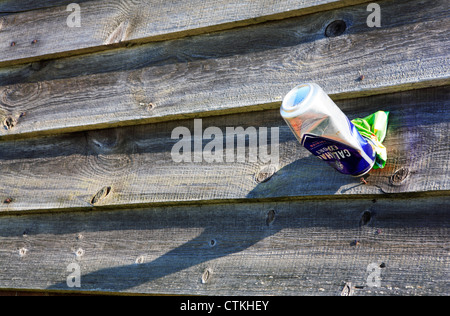 A crushed beer can and crisp packet left on wooden boarding on the North Norfolk coast. Stock Photo