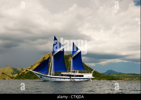 A 108 foot traditional wooden Phinisi schooner, the 'Ombak Putih',  here sailing in Komodo National Park in eastern Indonesia. Stock Photo