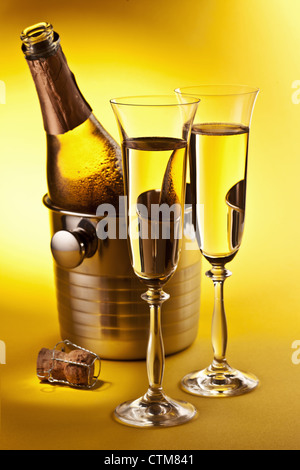 Champagne bottle in cooler and two champagne glasses. Isolated on a yellow. Stock Photo