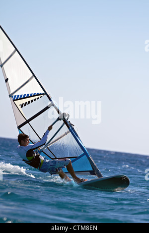 Side view of a windsurfer mooving horizontally close to water surface Stock Photo