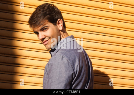 Portrait of a handsome young man smiling in front of a shutter Stock Photo
