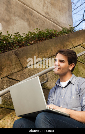 Thoughtful young man using laptop outdoors Stock Photo