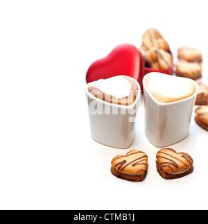 heart shaped cream cookies on red heart metal box and couple of cappuccino coffee cups Stock Photo