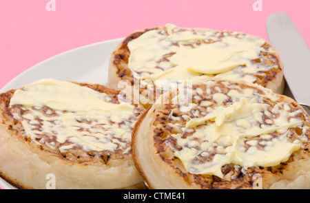 Buttered English crumpets served on a white china tea plate Stock Photo