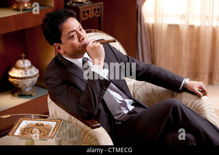 Mature businessman smoking cigar in a luxurious room Stock Photo