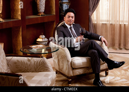 Mature businessman enjoying wine in a luxurious room Stock Photo