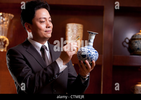 Mature businessman admiring an antique Chinese vase Stock Photo