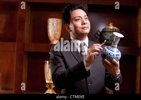 Mature businessman admiring an antique Chinese vase Stock Photo