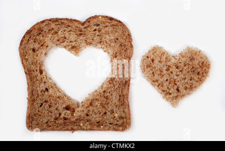 A slice of whole wheat bread with a heart shape cut from the center Stock Photo