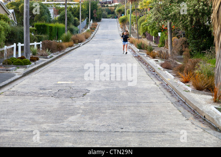 Girl jogging down Baldwin Street, Dunedin, New Zealand- the steepest residential street in the world Stock Photo