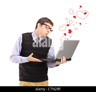 Young man giving a kiss on a laptop computer and red heart shapes around isolated on white background Stock Photo