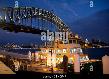 Ferry at Milsons Point wharf at night with Harbour Bridge and Opera House in background Sydney New South Wales Australia Stock Photo