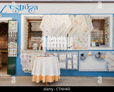 Burano island in Venice Lagoon famous for colourful painted buildings and houses  Here Pictured lace and other textiles on display in a shop in Burano Stock Photo