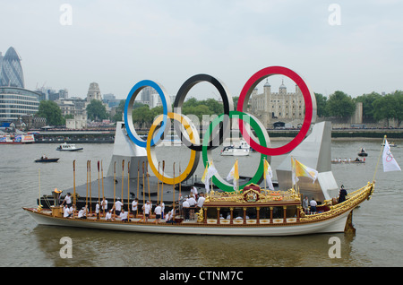 The Gloriana carrying the Olympic flame on the River Thames opposite The Tower of London moors next to Olympic rings  2012 Stock Photo