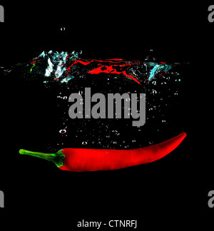 Red chili pepper sinking in water over black background Stock Photo