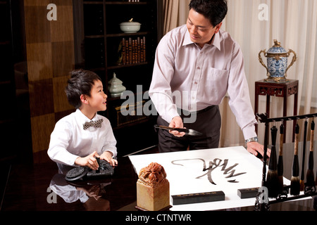 Grandpa and grandson practising Chinese calligraphy Stock Photo