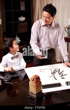 Grandpa and grandson practising Chinese calligraphy Stock Photo