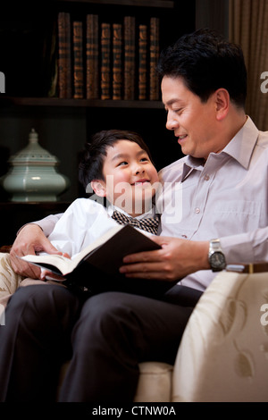 Grandpa and grandson reading book in study Stock Photo