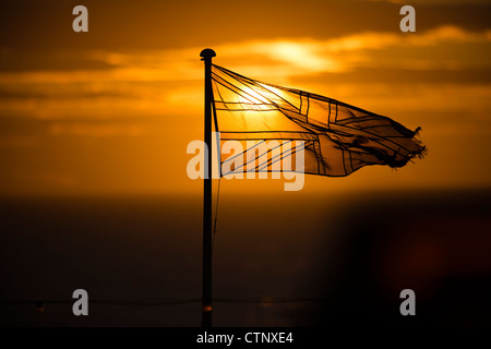 A sunset over an ol tattered semi transparent british flag union jack banner Stock Photo