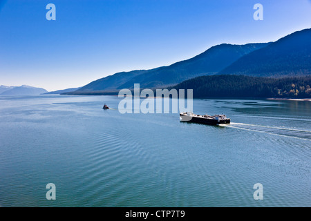 Aerial view tugboat towing cargo ship out Lynn canal Mount Roberts downtown Juneau in background Southeast Alaska Summer Stock Photo