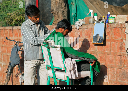 Hairdresser cutting boy's hair in the streets of Agra, Uttar Pradesh, India Stock Photo