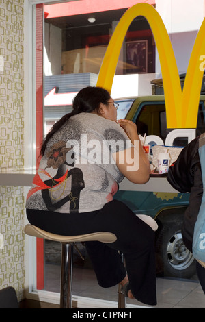 obese female eating fast food in restaurant indonesia Stock Photo