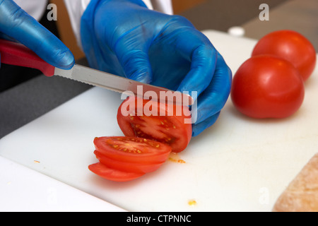 Shot of hands of chef wearing gloves, cutting fresh beef on board ...