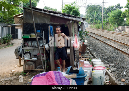 run down shack serving as a home and shop next to busy commuter railway line jakarta indonesia Stock Photo