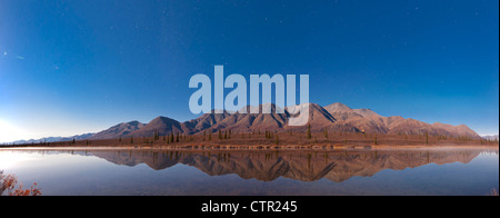 The foothills Alaska Range reflected in lake along Parks Highway under full moon Broad Pass Southcentral Alaska Autumn Stock Photo