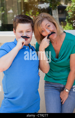 Mom and son are playing with fake mustaches. Stock Photo