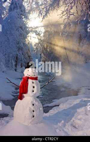 Snowman wearing red scarf black top hat standing in snow next small stream in foggy hoarfrost covered forest Russian Jack Park Stock Photo