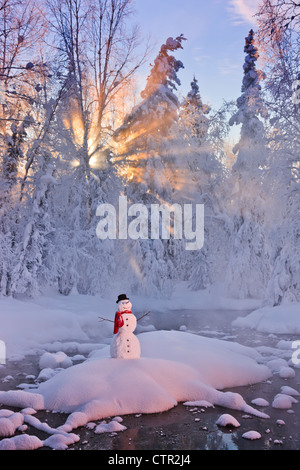 Snowman standing on small island in middle stream sunrays shining through fog hoar frosted trees in background Russian Jack Stock Photo