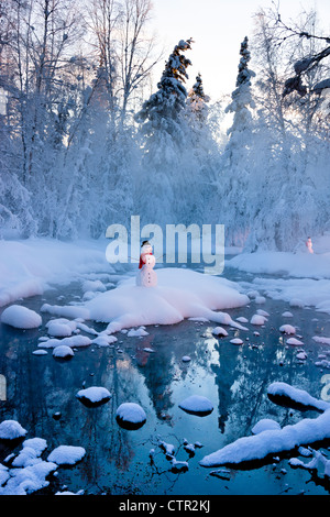 Snowman standing on small island in middle stream fog hoar frosted trees in background Russian Jack Springs Park Anchorage Stock Photo