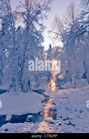 Snowman couple standing next stream sunrays shining through fog hoar frosted trees in background Russian Jack Springs Park Stock Photo