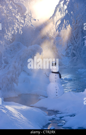 Snowman standing next stream sunrays shining through fog hoar frosted trees in background Russian Jack Springs Park Anchorage Stock Photo