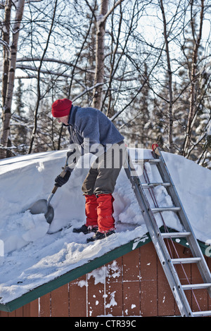 Man shovels snow from the roof of shed in Anchorage during a record snowfall year, Southcentral Alaska, Winter Stock Photo