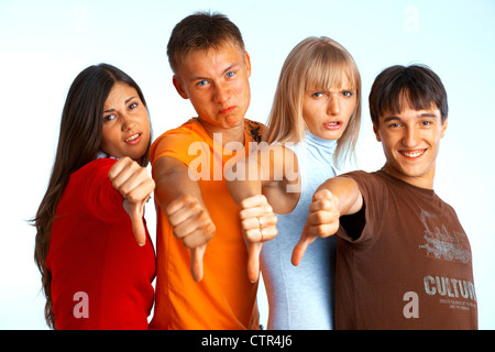 Four young people on white background and giving the thumbs-down sign. Stock Photo