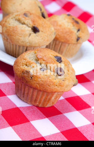 Homemade chocolate chip muffins on red gingham. Stock Photo