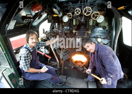 Train driver and fireman in the cab  of Southern Railway Steam Locomotive 'West Counry' Class Pacific 4-6-2 Number 34028 'Eddystone' on the preserved Swanage Railway in Dorset UK Stock Photo