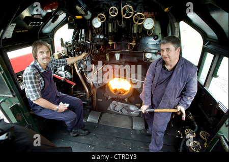 Train driver and fireman in the cab  of Southern Railway Steam Locomotive 'West Country' Class Pacific 4-6-2 Number 34028 'Eddystone' on the preserved Swanage Railway in Dorset UK Stock Photo