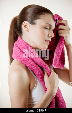 A young woman wearing fitness clothing wiping her face with a towel Stock Photo