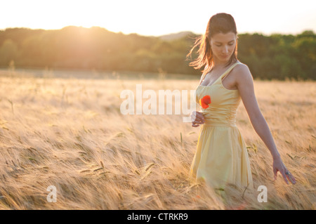 Woman walking through a wheat field, dreamily running her fingers over the wheat ears