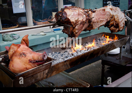 Hog spit roast on a barbecue with a pig's head in the foreground Stock Photo