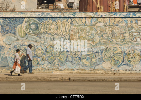 Two local Cubans walking past a graffiti art wall in central Havana Stock Photo