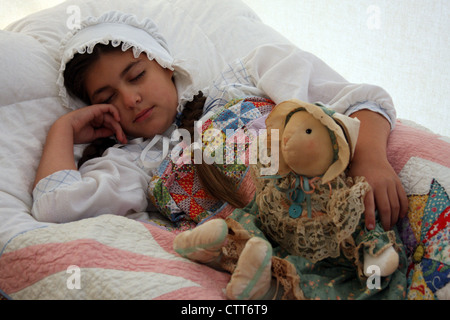 Girl sleeping on the bed with a rag doll Stock Photo - Alamy
