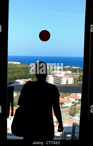 hotel room window with a female in silhouette against the outside view Stock Photo