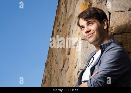 Smiling young man posing in front of a rocky wall Stock Photo