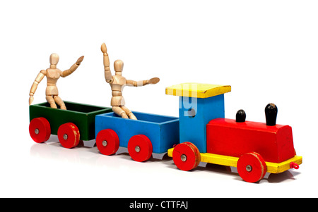 two wooden dolls sitting on a red yellow and green train Stock Photo